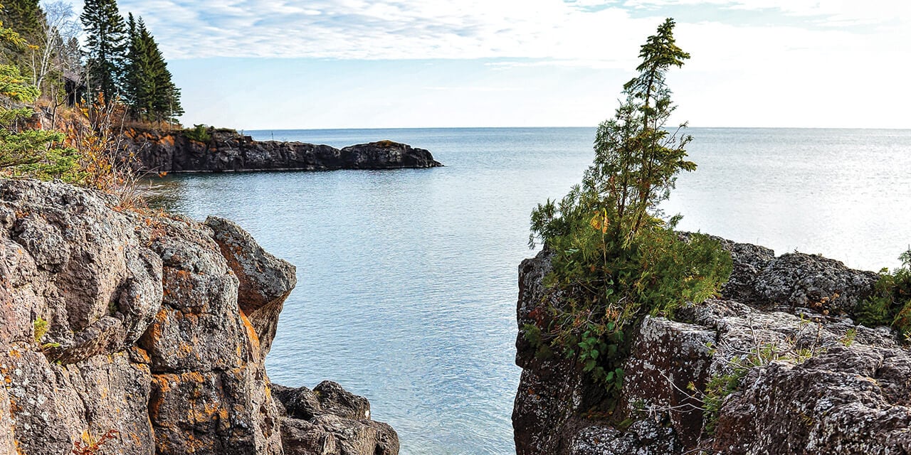 A divided rock wall overlooking a body of blue water