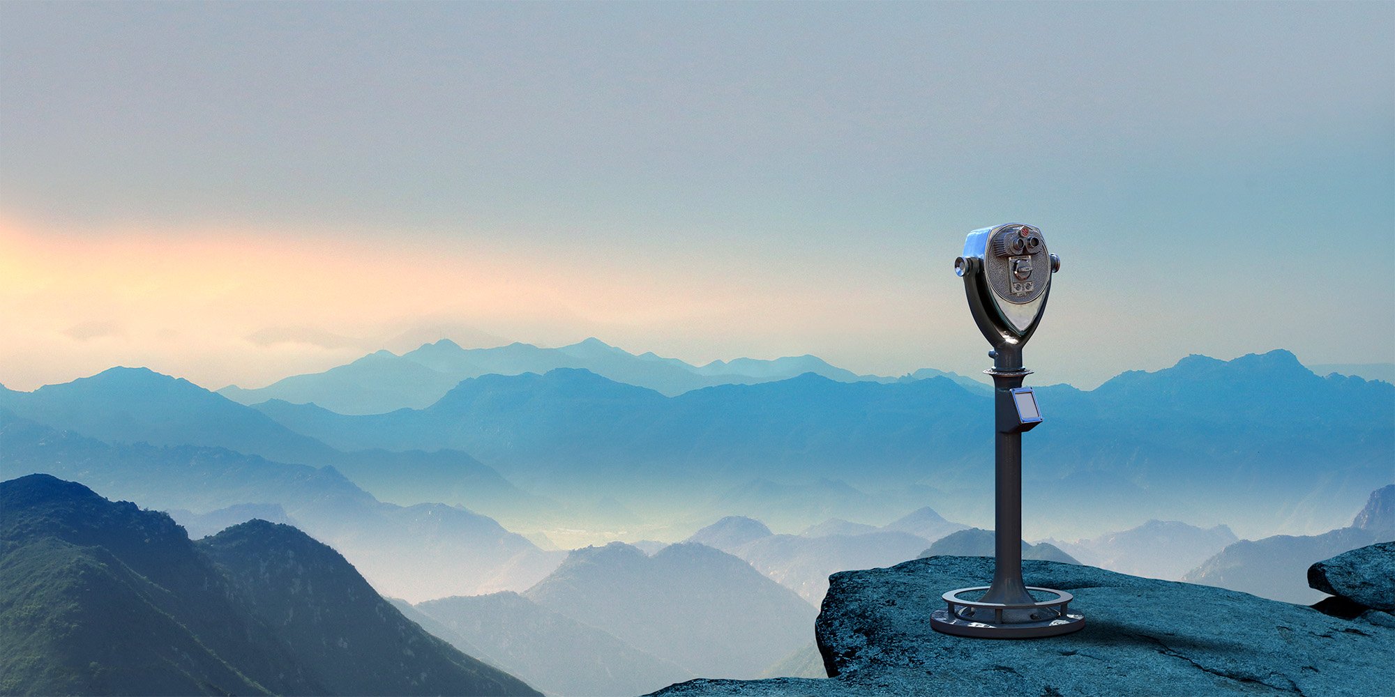 A telescope overlooking a vast mountain range at sunset