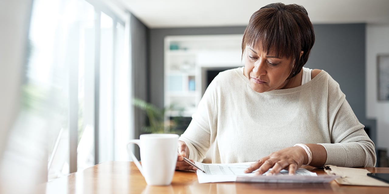 Woman sitting at table looking at paperwork.